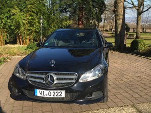 Schwarzer Mercedes Benz als Limousine auf dem Parkplatz vor einem Restaurant.